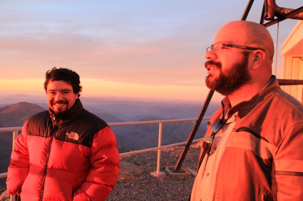 Two astronomers enjoy the sunset while disparaging the clouds which obscure observations